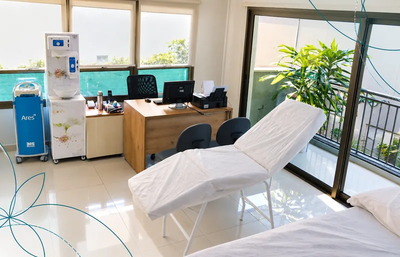 Sala de procedimentos da Clínica Holosi, com maca, equipamentos e janelas amplas